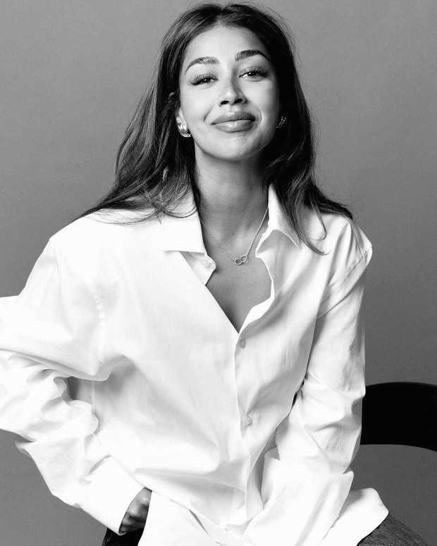 Aarti smiling in a white shirt, closely cropped