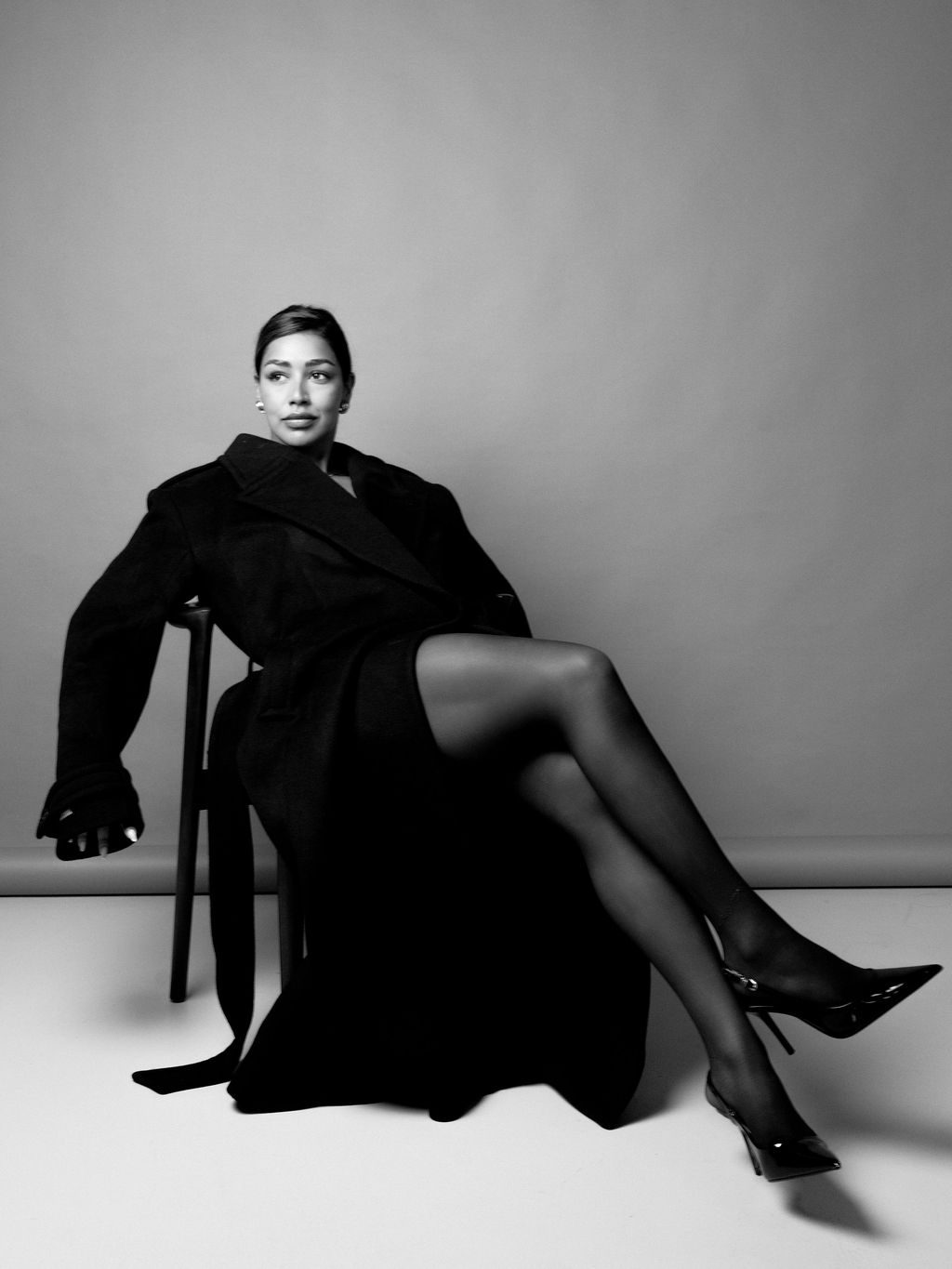 Aarti seated in a long black coat, looking straight into the camera